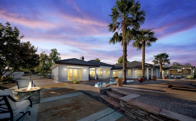 back house at dusk featuring an outdoor fire pit and a patio area