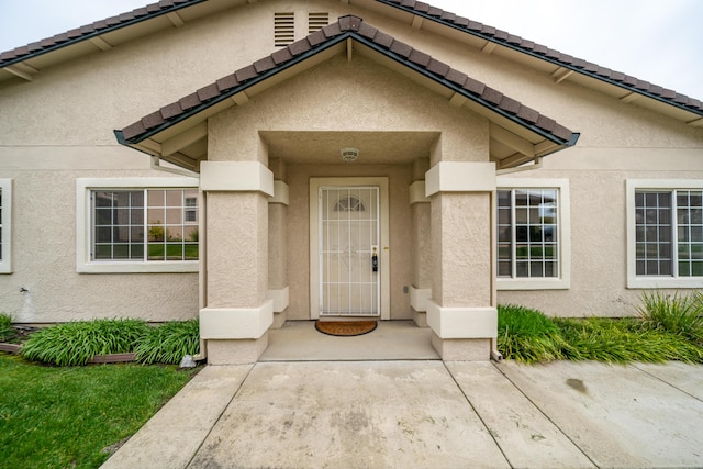 property entrance featuring a tiled roof and stucco siding