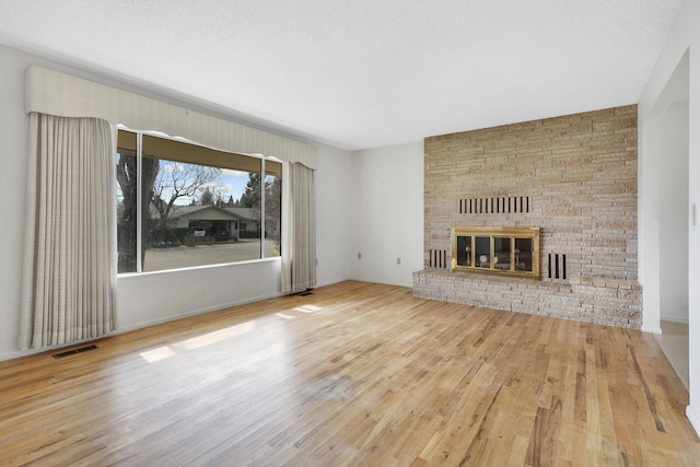 unfurnished living room with wood-type flooring, a textured ceiling, and a fireplace