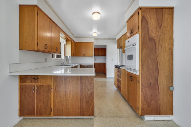 kitchen with sink, kitchen peninsula, and white oven