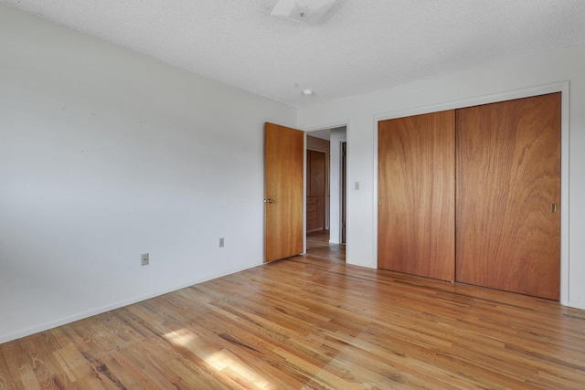 unfurnished bedroom featuring light hardwood / wood-style flooring, a textured ceiling, and a closet