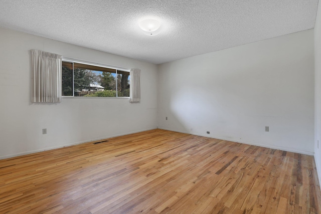 empty room with light hardwood / wood-style floors and a textured ceiling