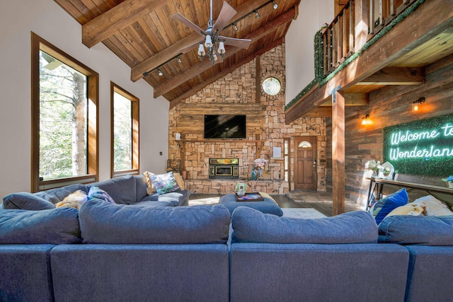 living area featuring a ceiling fan, wooden ceiling, a fireplace, high vaulted ceiling, and beam ceiling