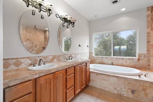 bathroom featuring vanity, tile patterned flooring, and tiled tub