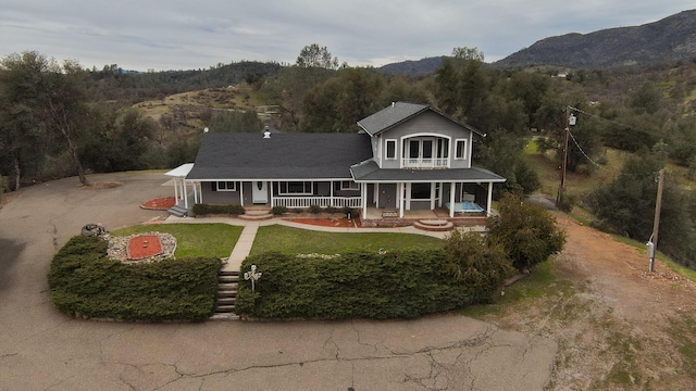 view of front of home featuring a mountain view, a front yard, and a porch