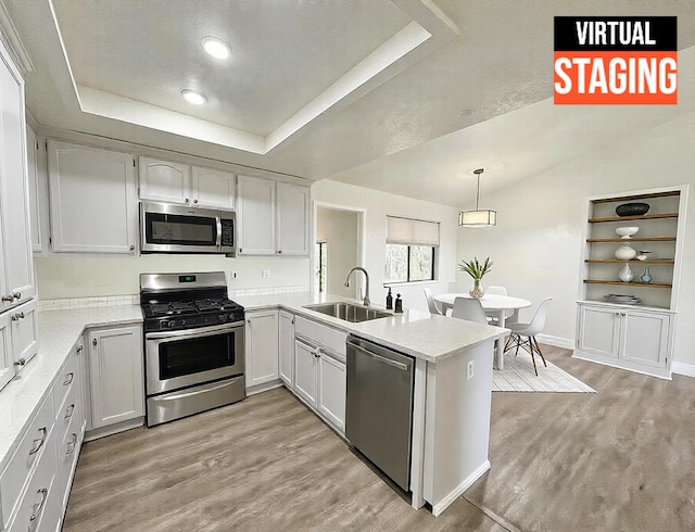 kitchen with sink, white cabinetry, stainless steel appliances, and kitchen peninsula