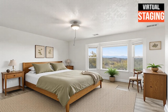 bedroom featuring a mountain view, wood-type flooring, and a textured ceiling