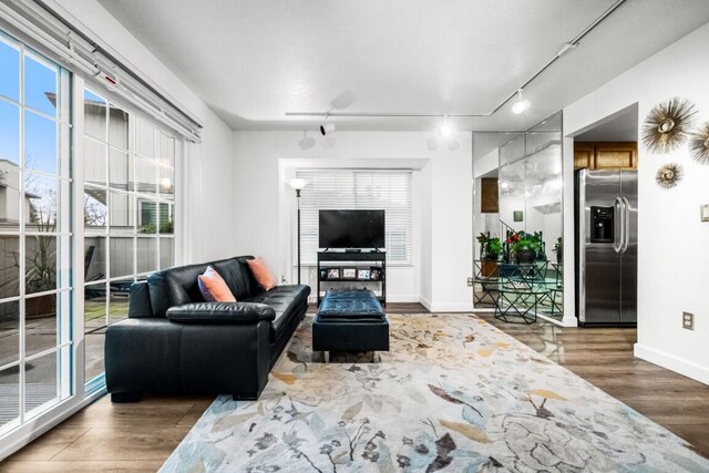 living area with track lighting, wood finished floors, and baseboards