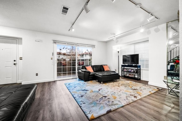 living room with wood finished floors, visible vents, and rail lighting