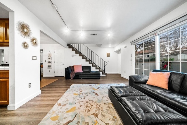 living area with baseboards, visible vents, stairway, and wood finished floors