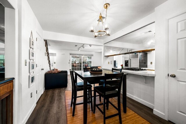 dining space with dark wood-style flooring, an inviting chandelier, and baseboards