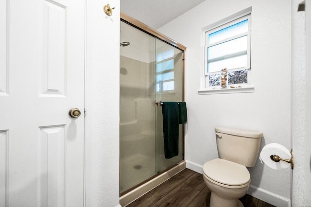 bathroom with a stall shower, toilet, baseboards, and wood finished floors