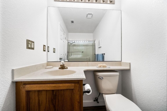 full bathroom featuring a textured wall, toilet, visible vents, vanity, and an enclosed shower