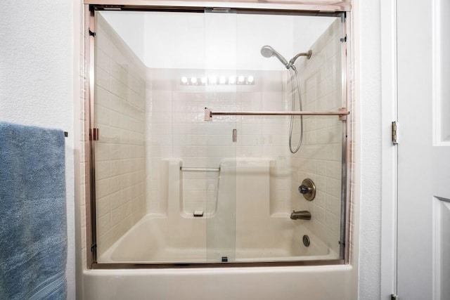 full bathroom with enclosed tub / shower combo and a textured wall