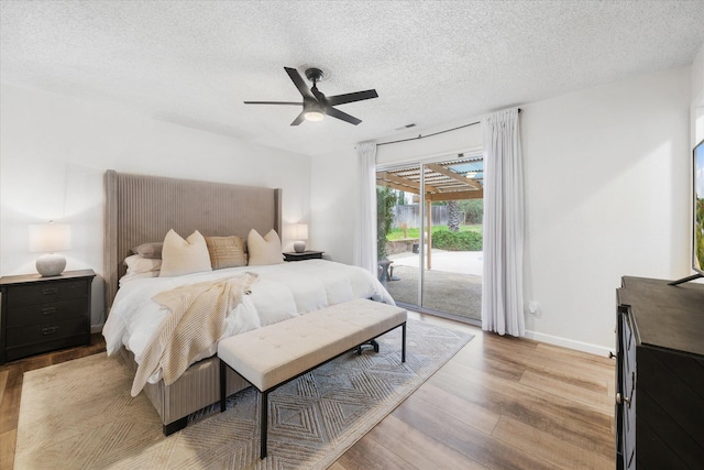 bedroom featuring a textured ceiling, ceiling fan, light wood-style flooring, baseboards, and access to outside