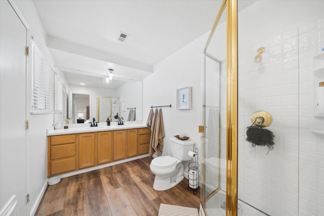 bathroom with wood finished floors, a sink, visible vents, double vanity, and a stall shower