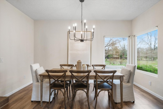 dining area featuring a notable chandelier, a textured ceiling, baseboards, and dark wood-type flooring