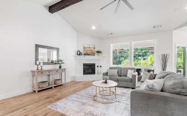 living room with light wood finished floors, visible vents, baseboards, beamed ceiling, and a high end fireplace