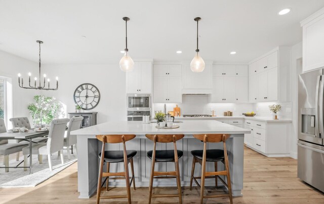 kitchen with white cabinetry, stainless steel appliances, light countertops, and a center island