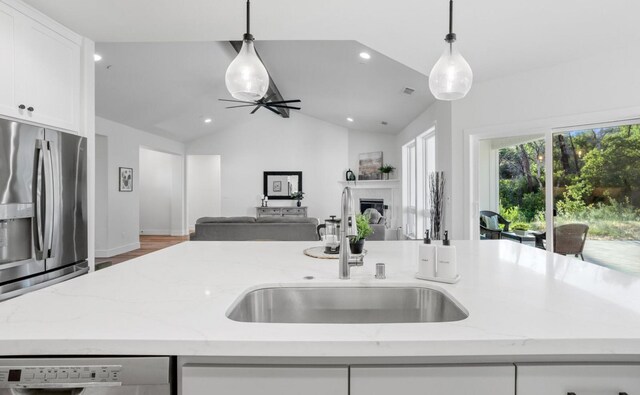 kitchen with hanging light fixtures, light stone counters, white cabinets, and stainless steel fridge with ice dispenser