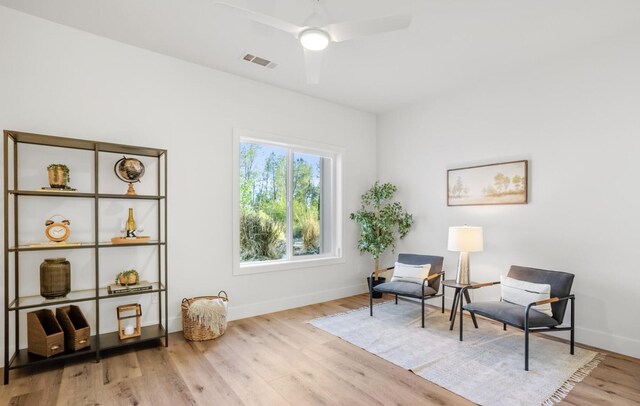 living area with a ceiling fan, light wood-type flooring, visible vents, and baseboards