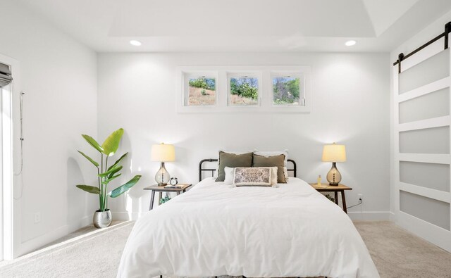 bedroom with recessed lighting, light carpet, baseboards, and a barn door