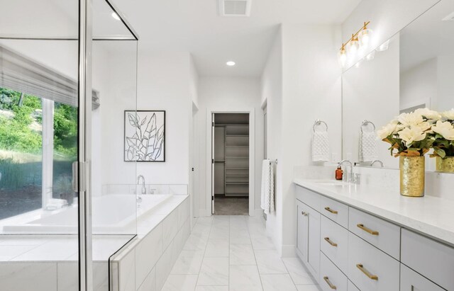 bathroom featuring a walk in closet, recessed lighting, visible vents, vanity, and a bath