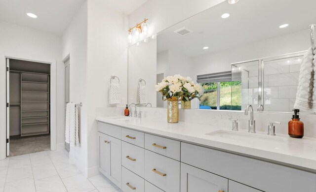 bathroom with a walk in closet, a sink, recessed lighting, and double vanity