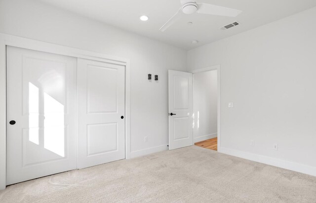 unfurnished bedroom with baseboards, visible vents, a closet, and light colored carpet