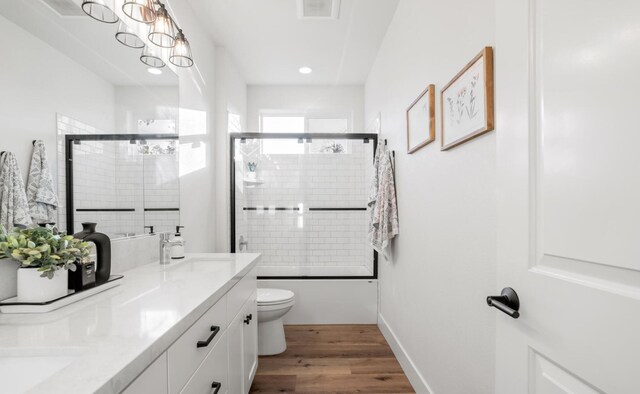 bathroom with toilet, wood finished floors, visible vents, a sink, and double vanity