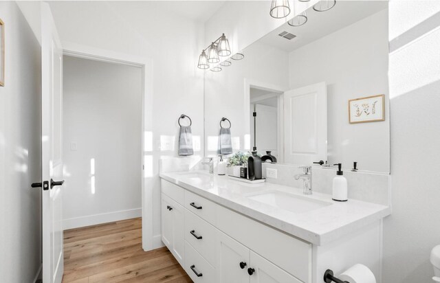 full bathroom featuring double vanity, wood finished floors, a sink, and visible vents