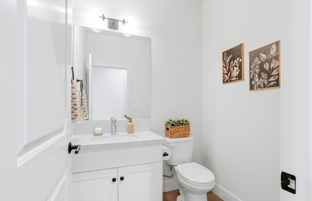 bathroom featuring baseboards, vanity, and toilet