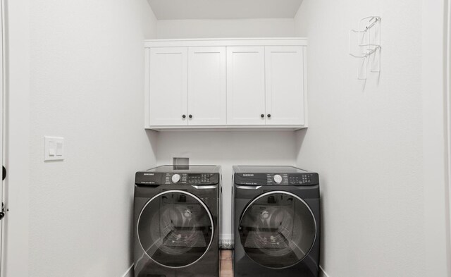 clothes washing area featuring washer and clothes dryer and cabinet space