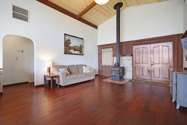 living room with high vaulted ceiling, a wood stove, visible vents, and dark wood finished floors