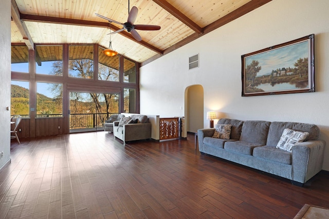 living area featuring arched walkways, wooden ceiling, dark wood-type flooring, visible vents, and beamed ceiling