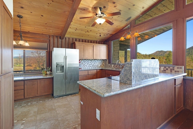 kitchen featuring a peninsula, plenty of natural light, stainless steel refrigerator with ice dispenser, and decorative backsplash