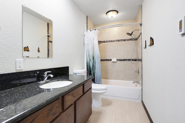 bathroom featuring toilet, a textured wall, shower / tub combo, and vanity