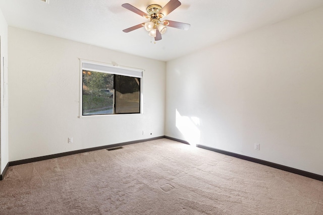 carpeted empty room featuring visible vents, ceiling fan, and baseboards