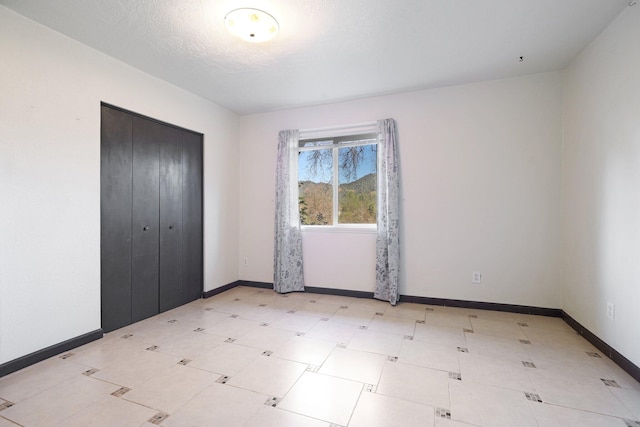 unfurnished bedroom with a closet, baseboards, a textured ceiling, and light floors