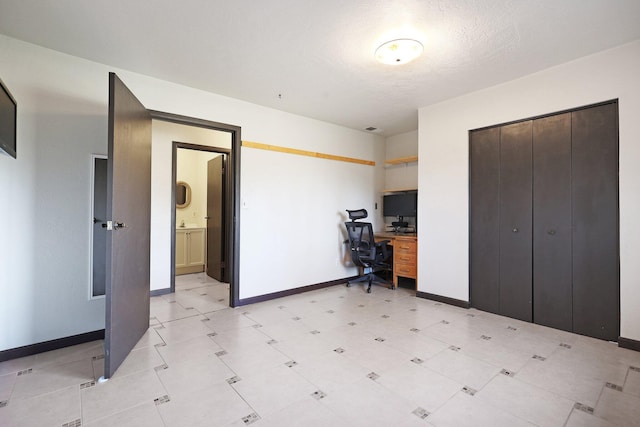 unfurnished office featuring light floors, baseboards, and a textured ceiling