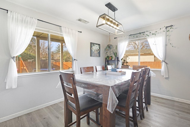 dining room with wood finished floors, visible vents, and baseboards