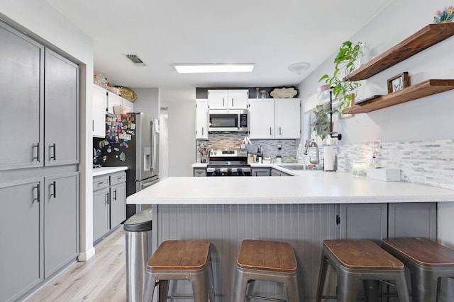 kitchen featuring tasteful backsplash, visible vents, appliances with stainless steel finishes, a sink, and a peninsula