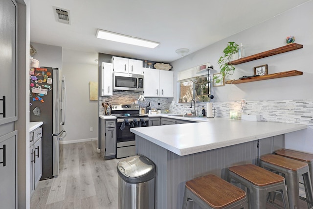 kitchen with a peninsula, a sink, visible vents, light countertops, and appliances with stainless steel finishes