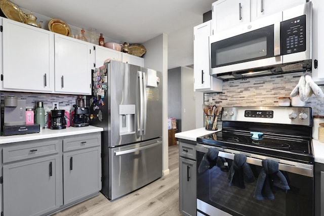 kitchen with light wood-style floors, stainless steel appliances, decorative backsplash, and light countertops