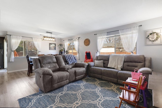 living area featuring a notable chandelier, plenty of natural light, baseboards, and wood finished floors