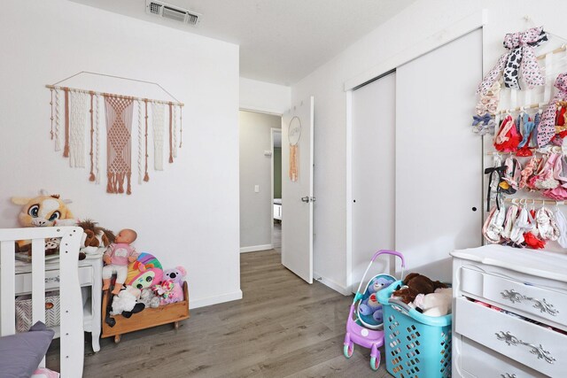 bedroom with baseboards, a closet, visible vents, and wood finished floors