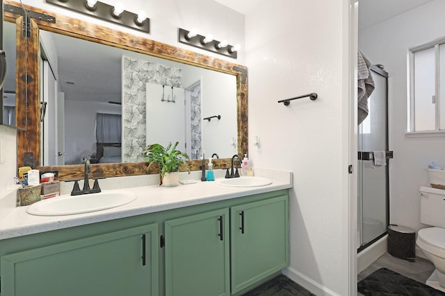 bathroom with toilet, double vanity, an enclosed shower, and a sink