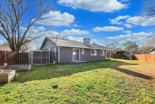 rear view of property with roof with shingles, a fenced backyard, a vegetable garden, and a lawn