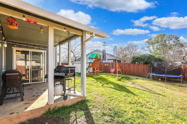 view of yard featuring a trampoline, a fenced backyard, a playground, and a patio