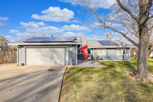 ranch-style house with an attached garage, roof mounted solar panels, fence, driveway, and a front lawn